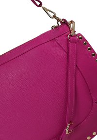 Fuchsia leren handtas met goudkleurige hardware, met een getextureerd oppervlak en studaccenten langs één rand. Verstelbare schouderriem inbegrepen.