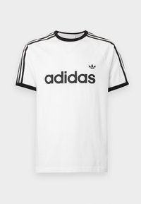 Biela bavlnená tričko s čiernym výstrihom a rukávmi. Obsahuje čierny dizajn s tromi pruhmi na pleciach a veľké čierne logo "adidas" na prednej strane.