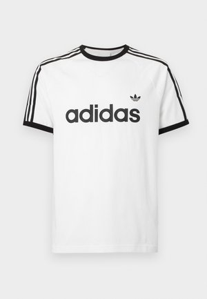 Biela bavlnená tričko s čiernym výstrihom a rukávmi. Obsahuje čierny dizajn s tromi pruhmi na pleciach a veľké čierne logo "adidas" na prednej strane.