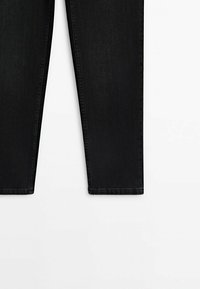 Jean en denim noir, visible du milieu de la cuisse jusqu'à l'ourlet avec des jambes droites et des coutures apparentes sur fond blanc.
