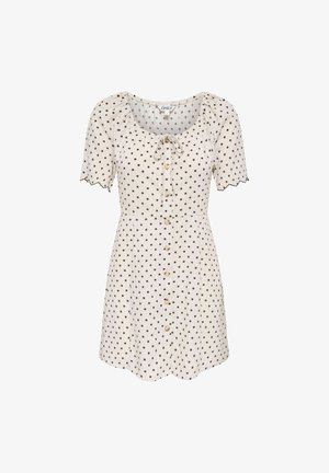Robe crème à manches courtes avec des pois noirs, boutons sur le devant, bords de manches festonnés et un nœud à l'encolure dégagée.
