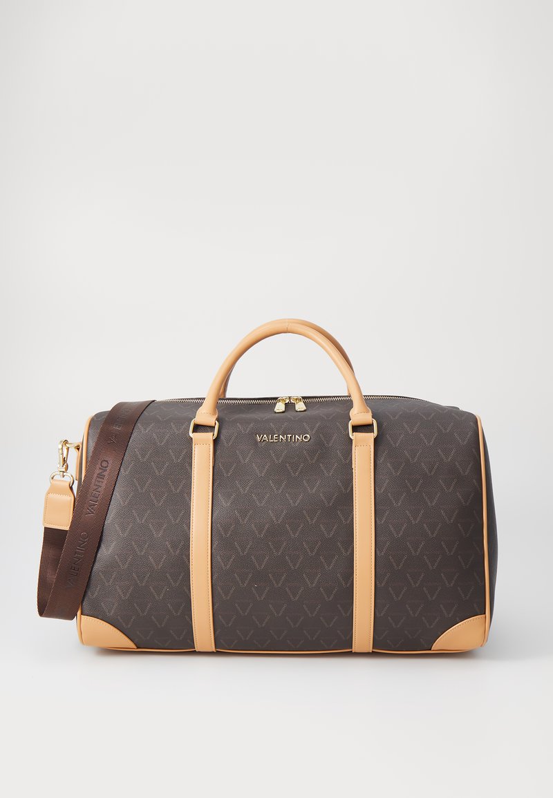 Brown patterned duffle bag with tan leather accents, gold hardware, double handles, and adjustable shoulder strap featuring logo detailing.