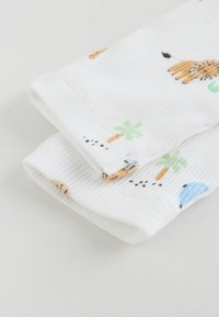 Tissu blanc côtelé avec un motif répétitif d'animaux de dessin animé, de palmiers et de petits points en orange, vert et bleu.