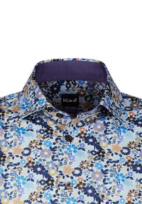 Camicia con motivo floreale nei toni del blu, viola e marrone. Presenta un colletto strutturato, bottoni scuri e una superficie del tessuto liscia. Taglia M.