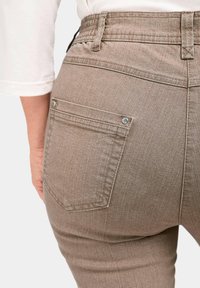 Braune Denim-Jogginghosen mit strukturiertem Finish, ausgestattet mit einer Gesäßtasche mit Nähdetails und silbernen Nietenakzenten. Sichtbarer verstellbarer Bund.