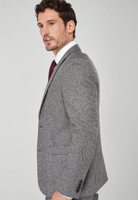 Blazer gri cu model în zigzag, cu o croială ajustată, având rever în formă de notch, închidere cu două nasturi și accente cu patru nasturi pe manșete.