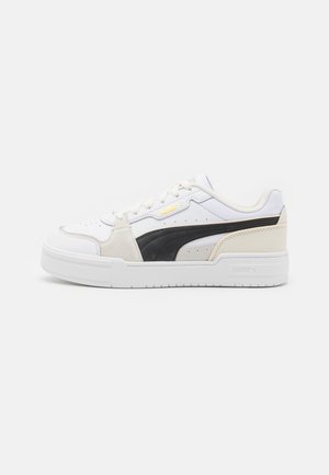 Weiße und schwarze Sneaker aus Wildleder und Leder mit einer chunky weißen Sohle, goldfarbener Markenprägung und perforiertem Zehendesign.