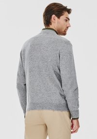 Szary sweter z dzianiny z ribbed rękawami i dołem, z zielonym akcentem na kołnierzu i gładką strukturą. Pokazany widok z tyłu.