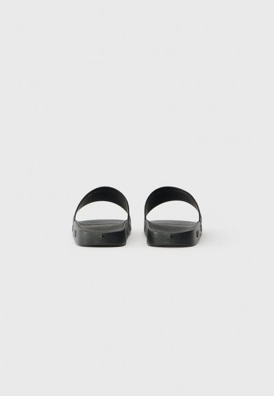 Pair of black slide sandals with single wide straps, viewed from the back on a plain white background.