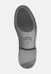 Suola delle scarpe realizzata in pelle grigia liscia con una leggera lucentezza. Presenta il nome del marchio e la taglia in rilievo, con borchie metalliche per una migliore aderenza.