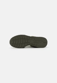 Zöld gumi sneaker talp, amely textúrázott tapadási mintával és kiemelkedő logóval rendelkezik. A design lapos, alacsony profillal bír.