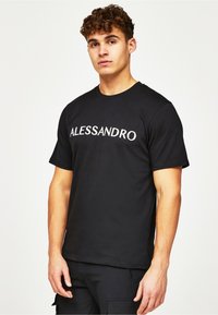 Mustat puuvillapaita, jossa on valkoisella brodeerattu "ALESSANDRO" teksti rinnan kohdalla; lyhyet hihat ja pyöreä pääntie.
