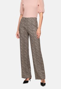 Leopard print wide-leg pants made of soft fabric, featuring a neutral beige base with dark brown spots, paired with black high-heeled shoes.