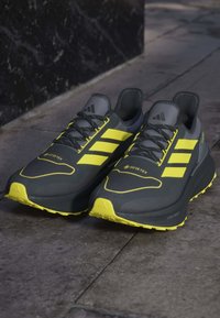 Sneaker Adidas grigie e gialle con GORE-TEX, caratterizzate da una tomaia testurizzata, dettagli riflettenti e una suola robusta per una buona trazione.