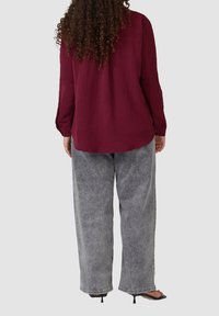 Bordeaux gekleed shirt met lange mouwen, gecombineerd met losse grijze denim broek. Zwarte open teen hakken maken de outfit compleet.
