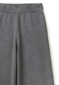 Pantalones de punto grises con un diseño de pierna ancha. Presentan una cinturilla elástica gruesa y piping blanco a los lados para un contraste. Textura suave.