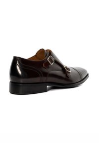 Dark brown leather shoe with a polished finish, featuring a sleek design, double buckle accents, and a rounded toe. Flat rubber sole.
