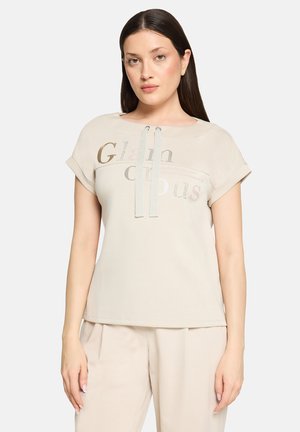 Beiges Kurzarmoberteil mit rundem Ausschnitt, mit glänzendem Text "Glam" und "Cious". Mit zwei dekorativen Bändern in Hellblau.