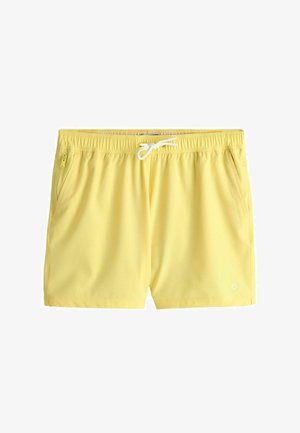 Shorts de bain jaunes avec taille élastique, cordon blanc, poches latérales et petit logo près de l'ourlet sur la jambe droite.