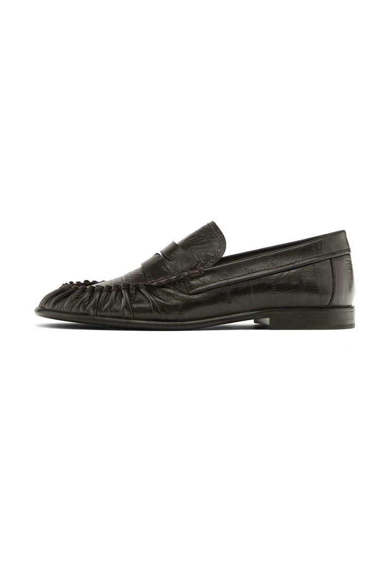 Sorte læder loafers med en frynsedesign på tåen, flad sål og en stikløs detalje over toppen. Glat tekstur og minimalistisk stil.