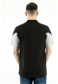 Zwart en grijs polo-shirt met korte mouwen en een kraag, voorzien van contrasterende accentkleuren op de mouwen en een zachte katoenmix textuur.