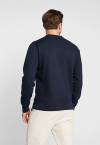 Sudadera de color azul marino con cuello redondo, puños y dobladillo acanalados, hecha de una suave mezcla de algodón con una textura lisa.