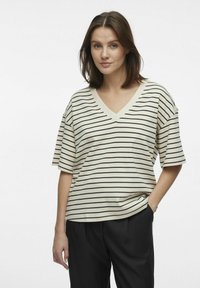 V-hals t-shirt i creme med sorte vandrette striber, korte ærmer og en afslappet pasform. Fremstillet af blødt, letvægts bomuldsstof.