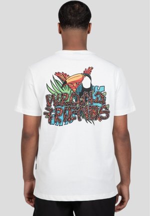 Camiseta blanca de algodón con un gráfico colorido de un tucán y follaje tropical en la parte posterior, con el texto "AMIGOS INCORRECTOS" en una fuente divertida.