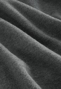 Tissu doux et gris avec une fine texture côtelée et de légers plis formant des vagues diagonales à la surface.