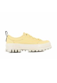 Zapatilla de lona amarilla con una suela de goma blanca gruesa. Presenta cordones redondos, costuras laterales y una lengüeta negra en el talón.