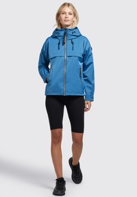 Blue waterproof jacket with a hood, featuring a front zip, adjustable straps, and black accents. Worn over black shorts and shoes.