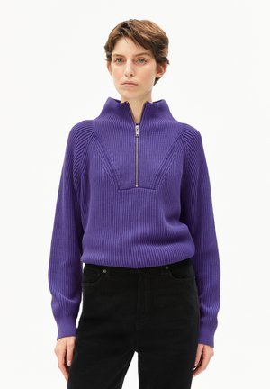 Maglione viola a coste con colletto alto e zip a metà. Presenta un design testurizzato e maniche lunghe, abbinato a pantaloni neri.