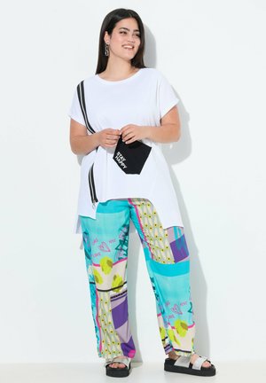T-shirt bianco a maniche corte con taschino zip nero. Pantaloni larghi a fantasia colorata con vari disegni in turchese e viola.
