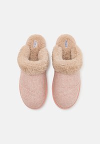Rosa tofflor med ett strukturerat tygöverkropp och en mjuk beige fuskpälskrage. Platt sula med en avslappnad design för enkelt på- och avtagning. TOMS-logotyp synlig.