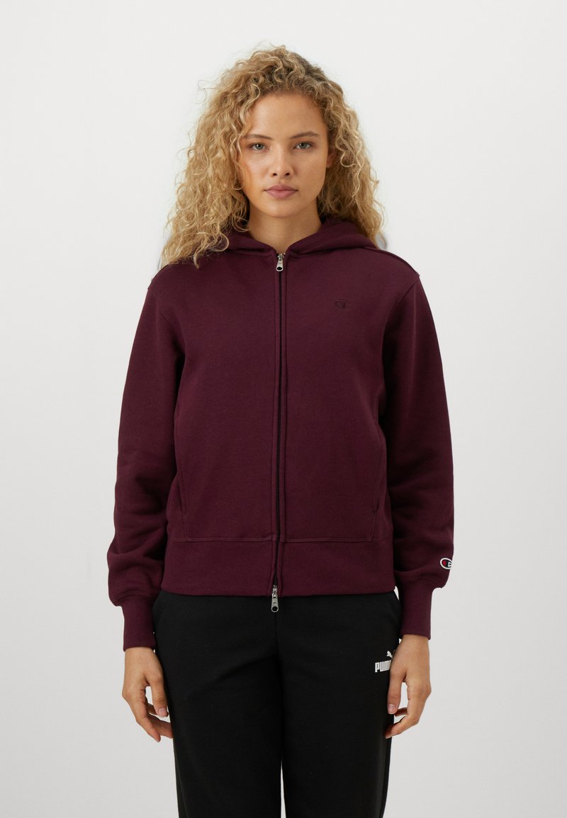 Burgundy zip-hoodie i bomullsblandning, med dragkedja fram, huva och ribbade muddar. Visad mot en neutral bakgrund.