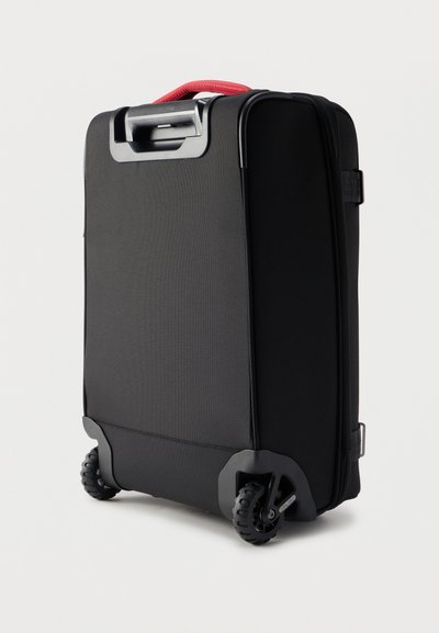 Μαύρη μαλακή βαλίτσα με κόκκινη λαβή, δύο τροχούς και ανασυρόμενη λαβή στην κορυφή, εμφανίζεται σε λευκό φόντο.