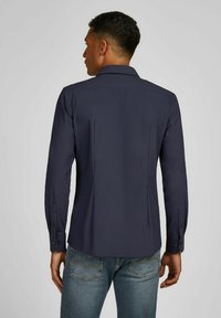 Marineblauw overhemd met lange mouwen en kraag, met een gladde textuur en knoopmanchetten. Ontworpen met een getailleerde pasvorm en subtiele rugplooien.