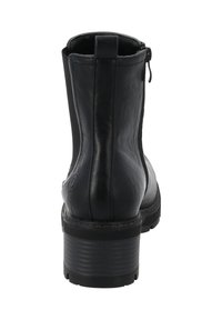 Bottine noire en cuir avec une finition lisse, une fermeture éclair sur le côté et un talon épais rayé. Présente un logo circulaire sur le côté extérieur.