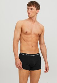 Boxer in cotone nero con elastico in vita brandizzato con la scritta "JACK & JONES" in bianco. Design aderente e texture liscia.