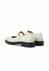 Zapatos Mary Jane de charol blanco con punta redondeada, correa ajustable y suela de goma negra. Textura suave con acabado brillante.