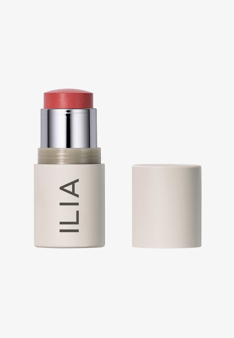 ILIA Cream Blush Stick mit einem korallenrosa oberen Teil, silbernen Akzenten und einem beigen zylindrischen Sockel. Abnehmbarer Deckel inklusive.