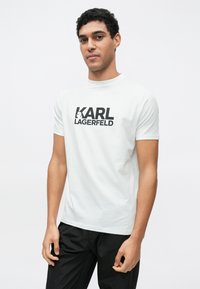 Λευκό βαμβακερό μπλουζάκι με μεγάλο μαύρο λογότυπο "KARL LAGERFELD" στο στήθος. Κοντά μανίκια και λαιμόκοψη στρογγυλή.