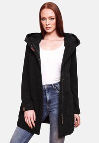 Black hooded coat with a zip front, two side pockets, and textured fabric. Worn over a white tank top and blue jeans.