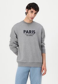 Felpa grigia con grafica navale "PARIS" e testo più piccolo sotto. Polsini e vita a costine, colletto rotondo, tessuto misto cotone.