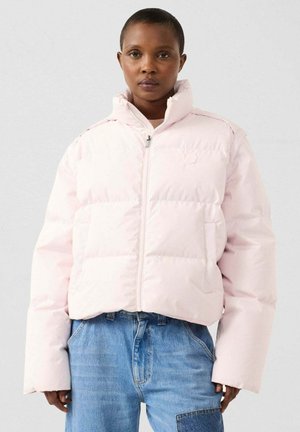 Puffer jacket in soft pink with a cropped design, zip closure, high collar, and padded sections, paired with blue denim jeans.