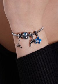 Zilveren charm bracelet met een assortiment charms: een initiaal 'A', een dolfijn en een blauwe orchidee met emaille details.