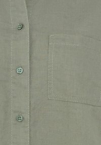 Light green linen shirt featuring a button closure, subtle texture, and a chest pocket with contrasting white stitching.