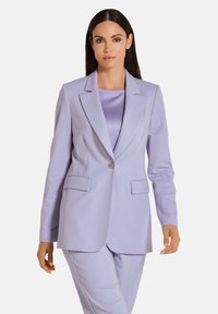 Op maat gemaakte lavendelkleurige blazer met notched kleppen, enkele knoopsluiting en twee voorkeizen. Stof is soepel en het ontwerp is slank.