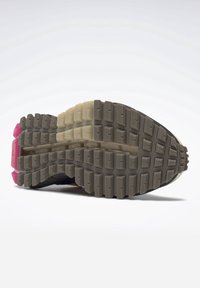 Suela de una zapatilla de correr que muestra una entresuela texturizada con patrones de rodadura rectangulares en colores gris, crema y rosa.
