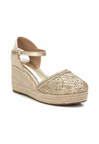Sandalo wedge in espadrilles dorate con cinturino alla caviglia, upper riccamente ricamato, suola intermedia in juta intrecciata e una soletta metallica liscia.